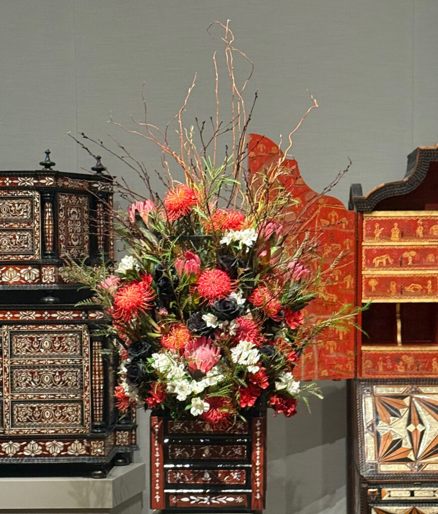 red and white floral art in front of two asian cabinets with black and red accents