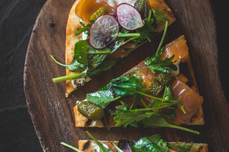 Three pieces of pizza with green lettuce and sliced radish