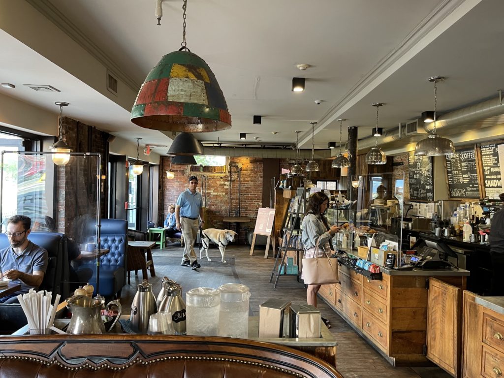 coffee with multi color later and counter on left with glass and woman paying