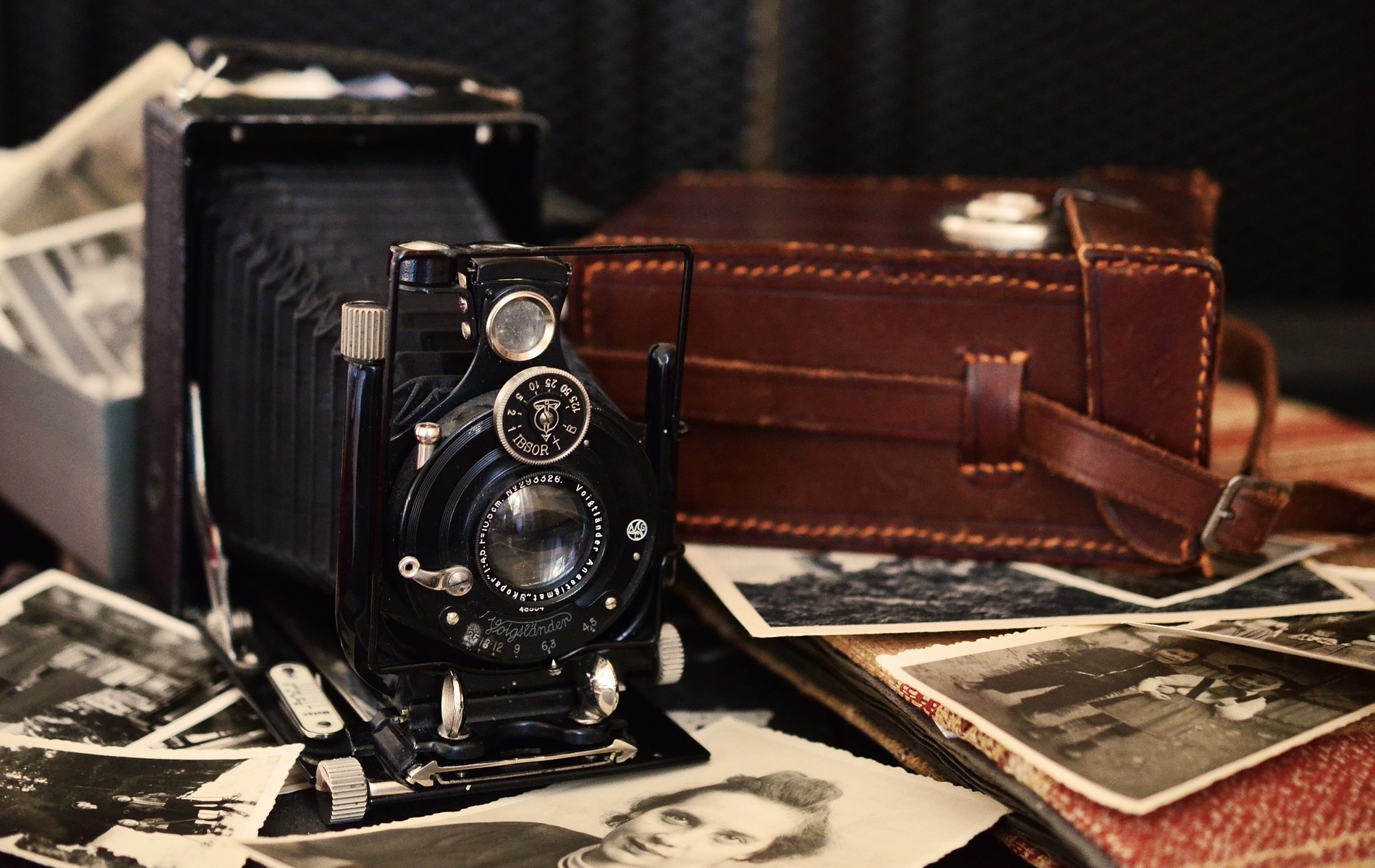 old fashioned camera on wood table with old photographs underneath