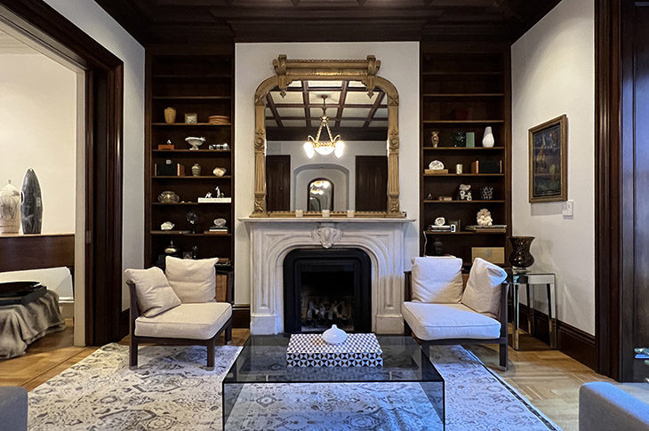 Victorian library, with gold gilt mirror, marble fireplace mantle, walnut bookcases, modern glass table and chairs.