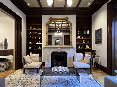 Victorian library, with gold gilt mirror, marble fireplace mantle, walnut bookcases, modern glass table and chairs.