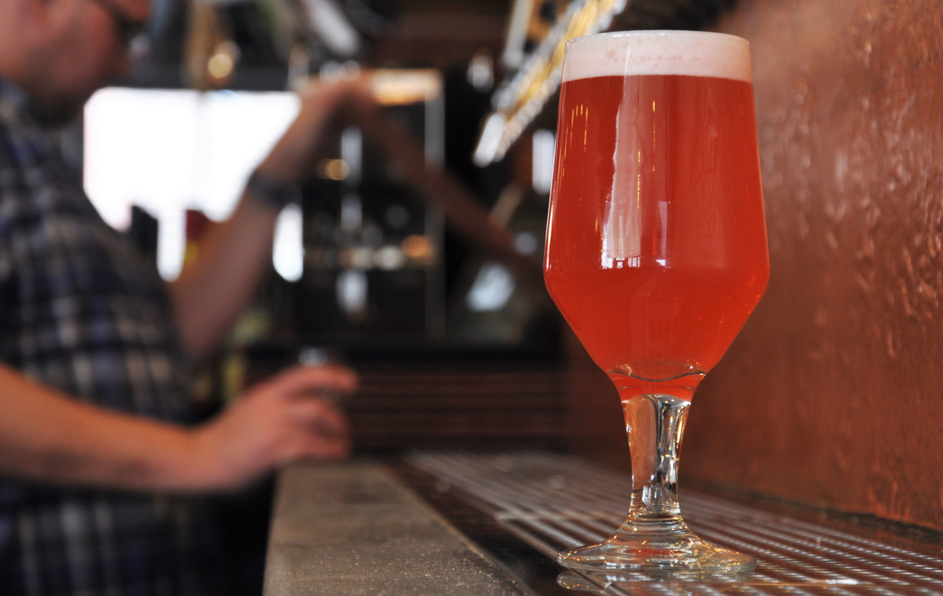 on the left a many pouring beer and the right an orange beer in a clear goblet