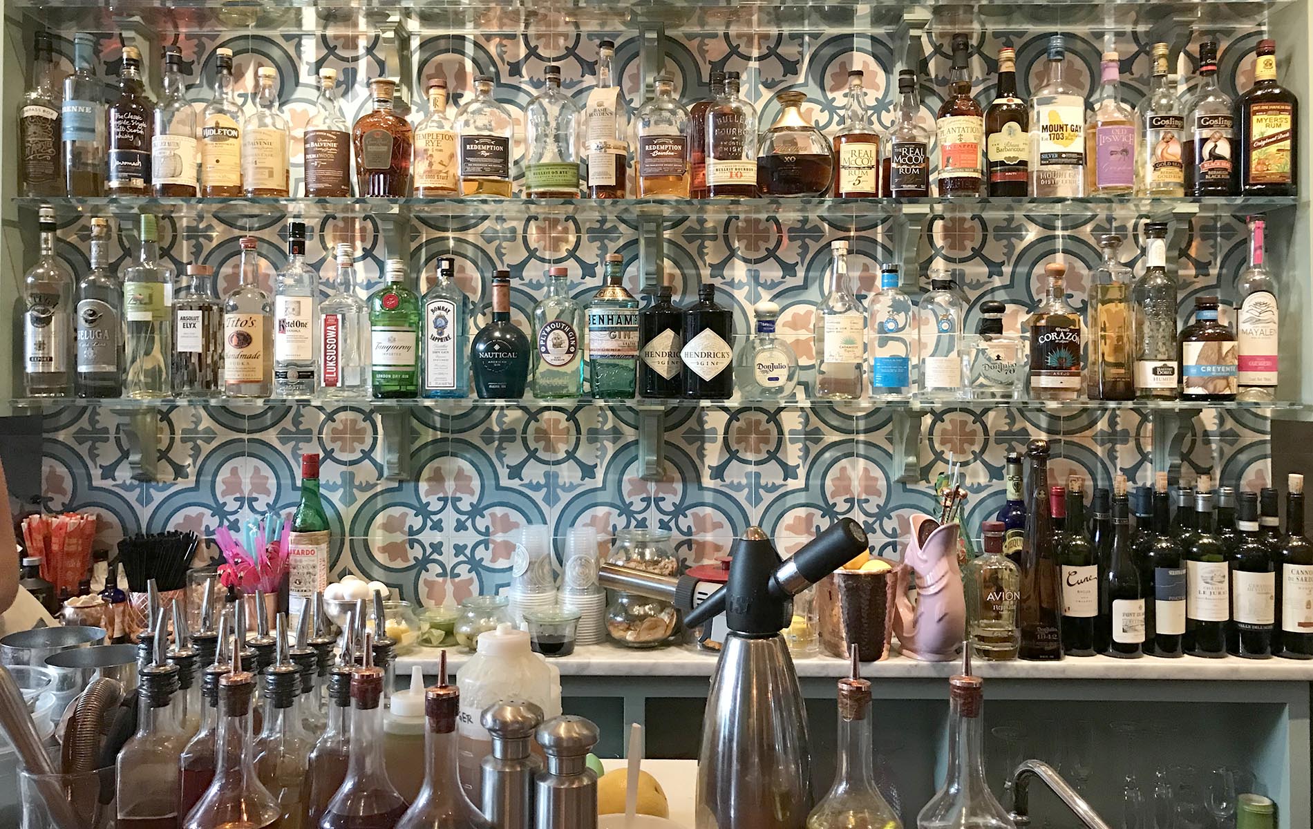 Colorful bar with bright blue tile and many bottles of alcohol