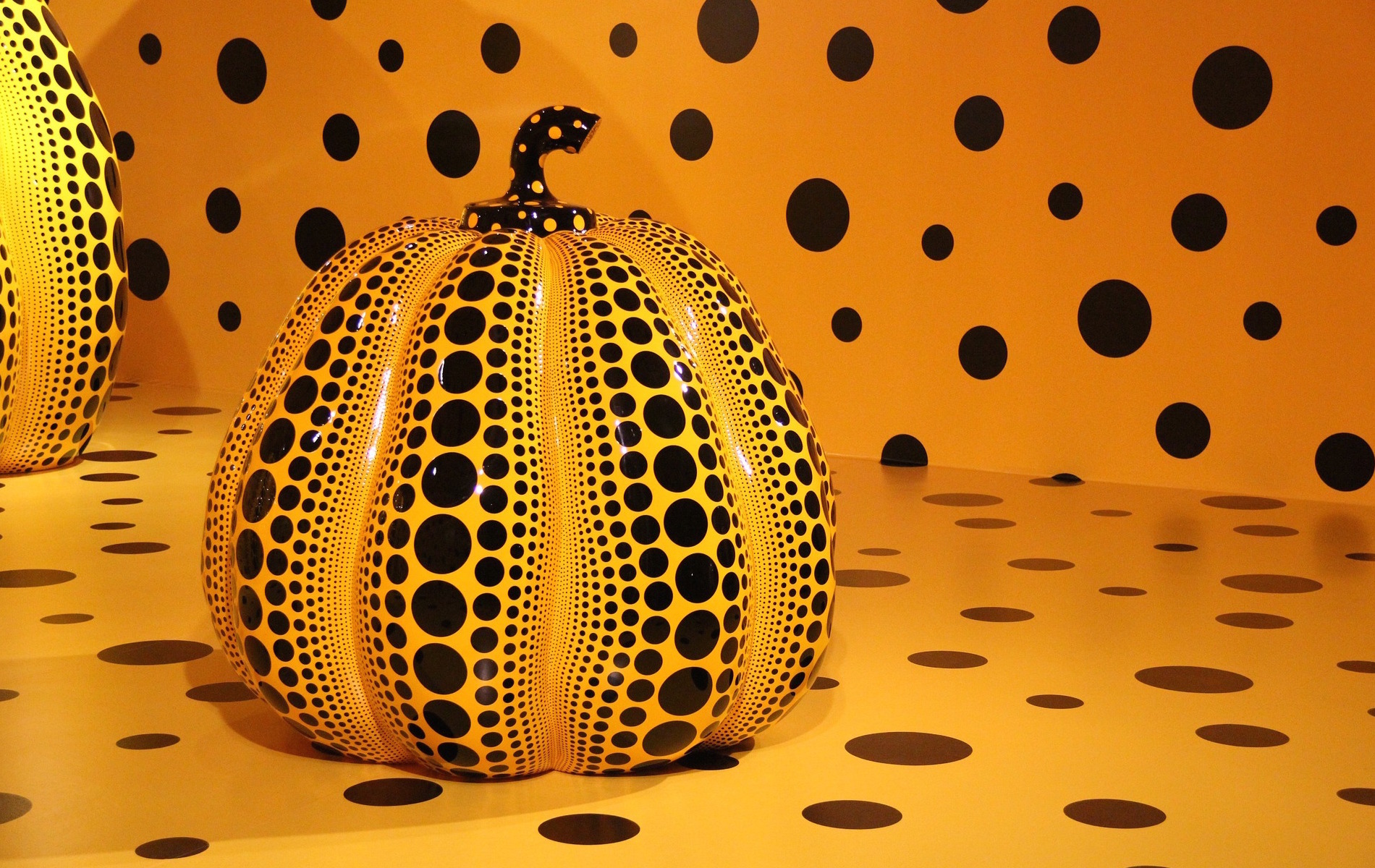 Orange pumpkin sculpture with black polka dots on same orange background with black dots