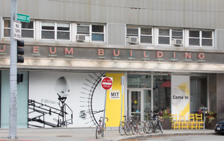 grey building that says museum with yellow sign next to door