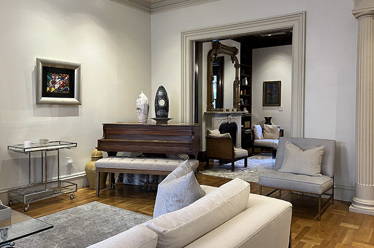 Gray painted room, light wood floors, large abstract wall hanging and stained wood grand piano