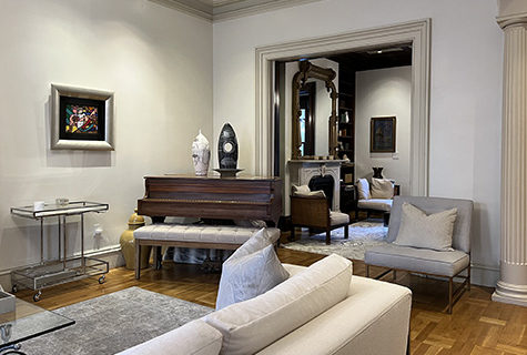 Gray painted room, light wood floors, large abstract wall hanging and stained wood grand piano