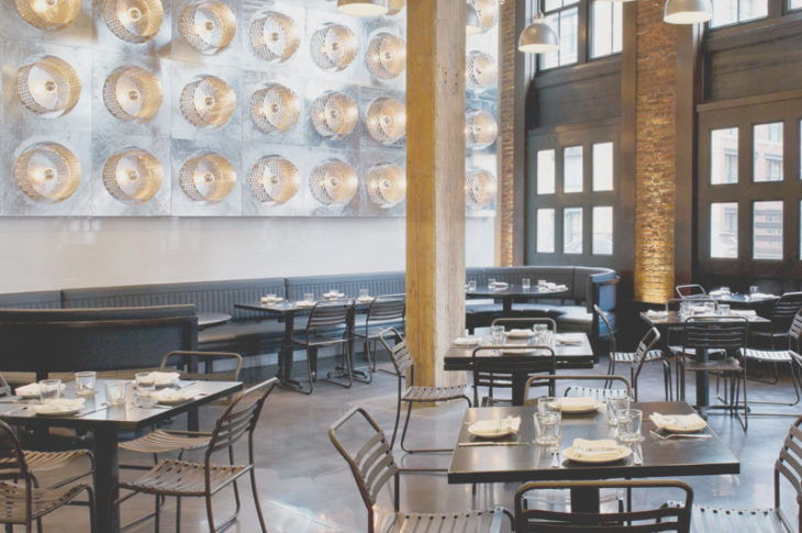 industrial dining room with 5 black tables and a silver wall with grid of lights