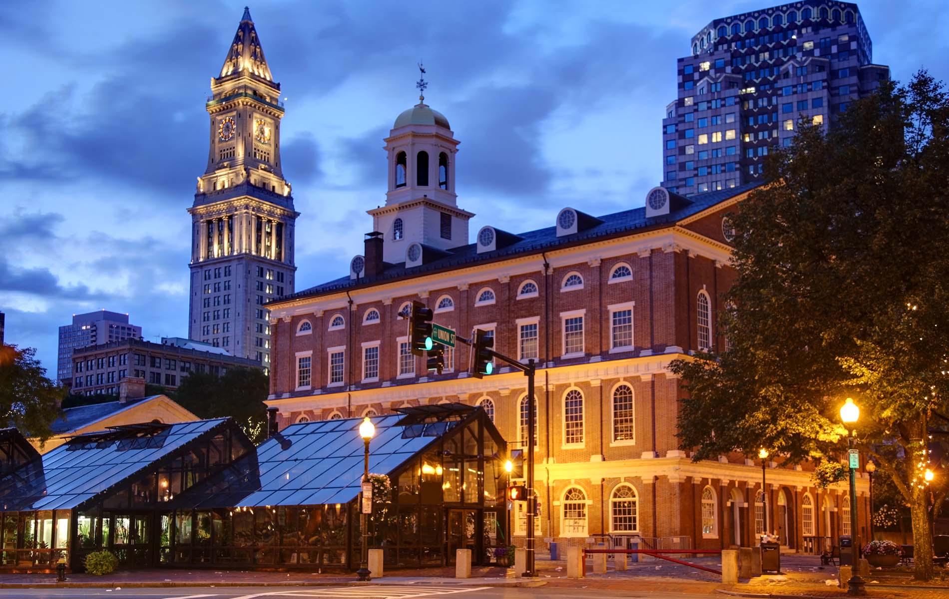 Night time sky with view of two illuminated towers on right and red brick building to left of quincy market