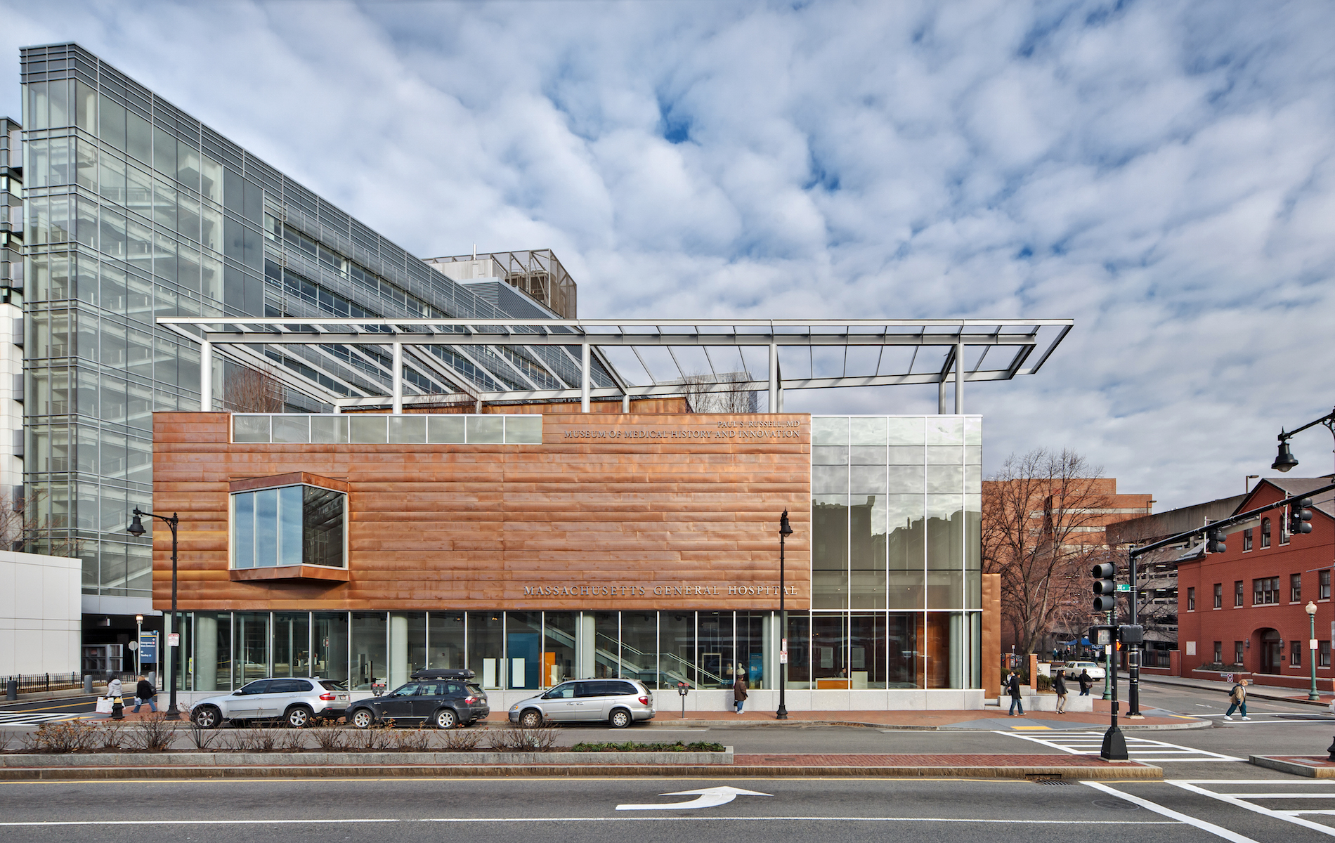 Blue sky with white clouds above a modern orange building with metal and glass