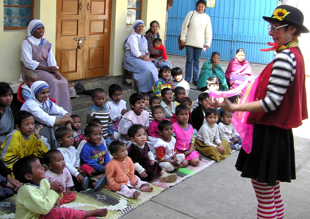 clown in red vest with black and white shirt performs for children in colorful outfits