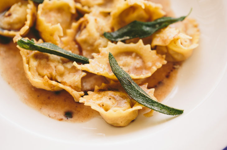 bowl of ravioli with 3 pieces of fried sage