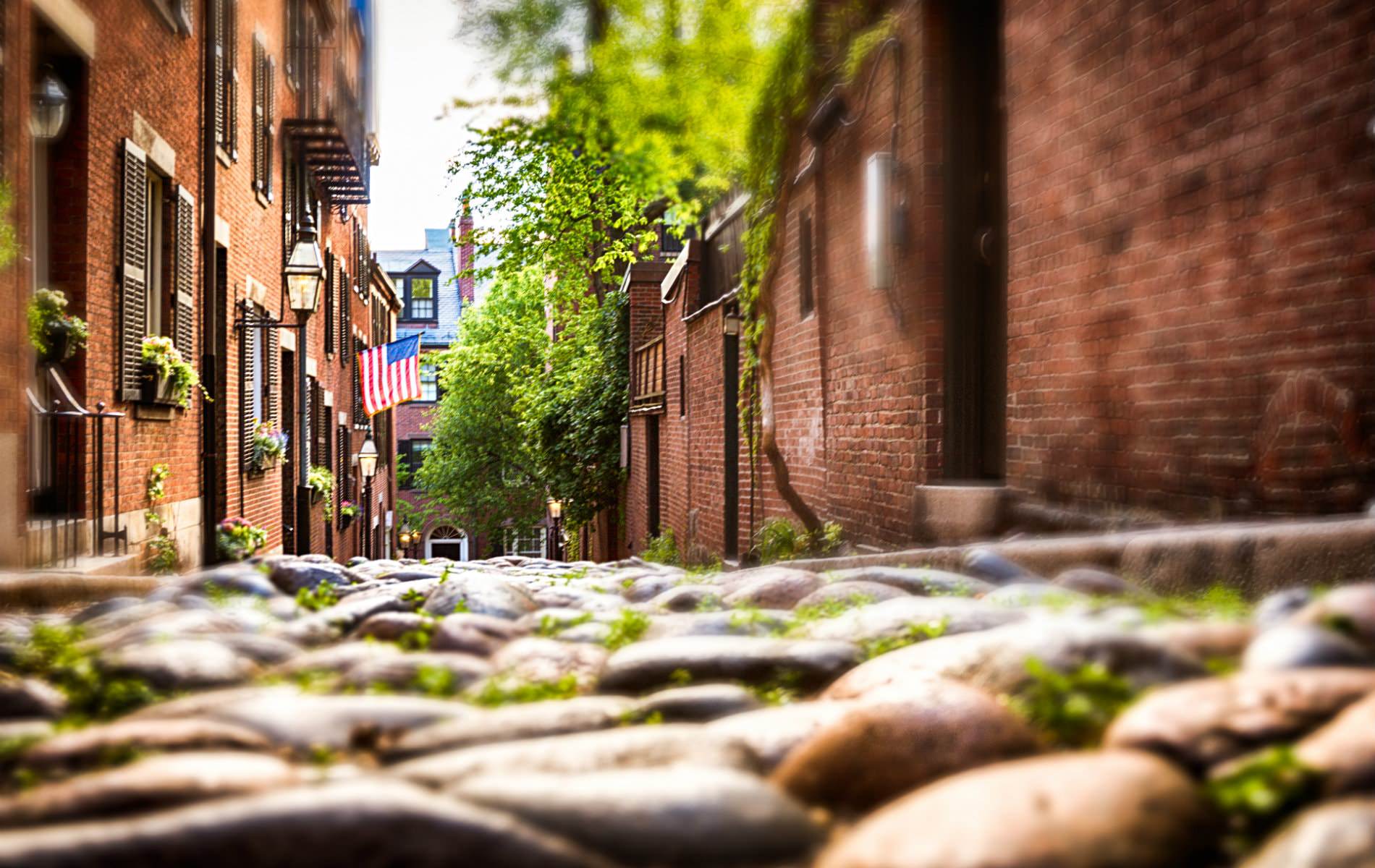 Ground level view of sloping stone alleyway between red brick buildings