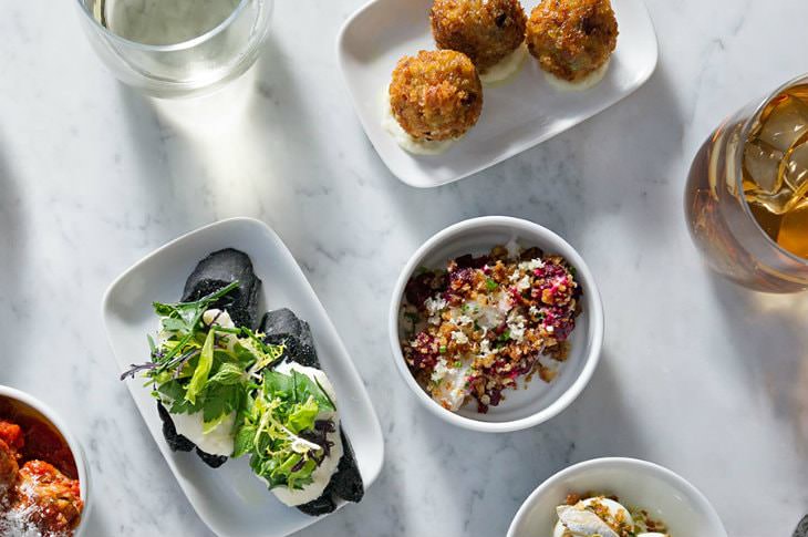 White bowls filled with colorful, artistic, gourmet dishes on a marble table