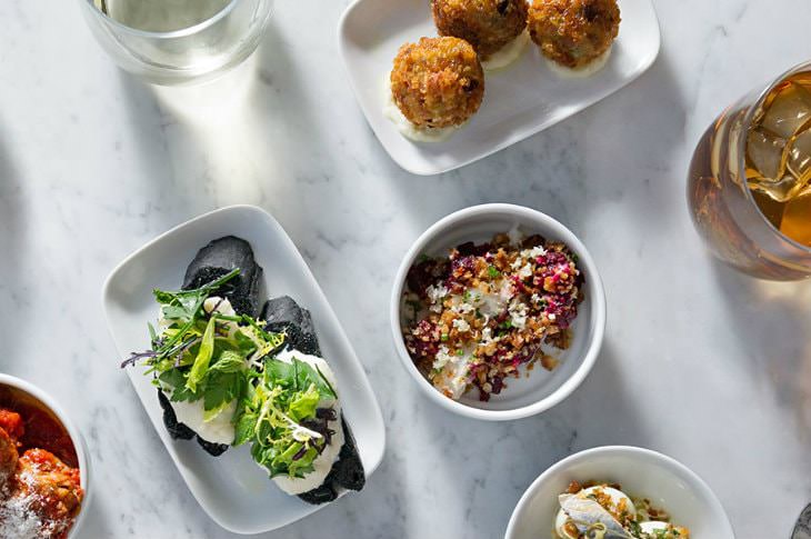 White bowls filled with colorful, artistic, gourmet dishes on a marble table