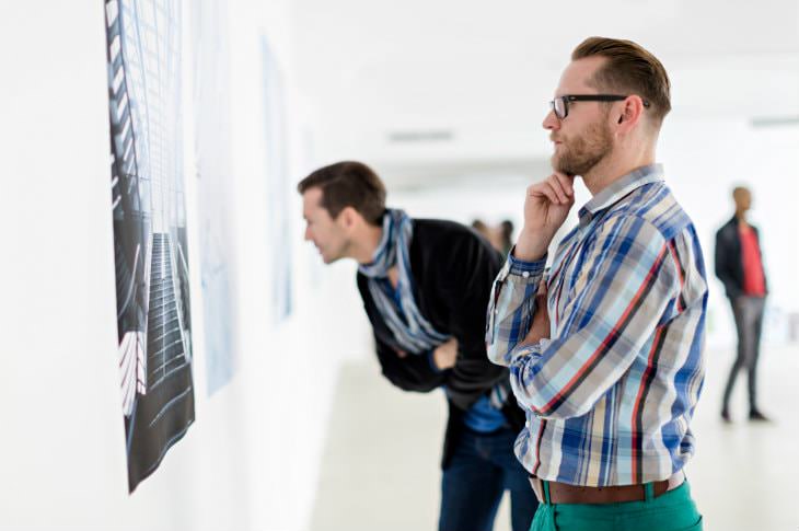 Two men contemplating a piece of art in a modern, white, brightly lit art gallery