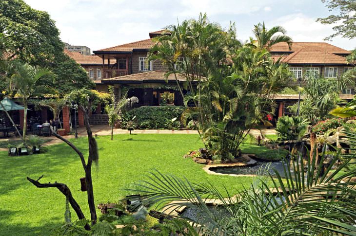 Wood-sided hotel surrounded by green grass, ponds, and tropical plants and trees