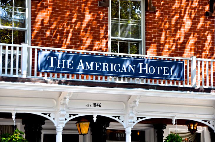 Close-up view of the American Hotel sign on a brick building with a white covered porch