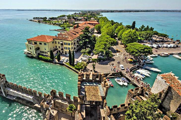 Luxury hotel on a peninsula surrounded by turquoise water next to a medieval castle