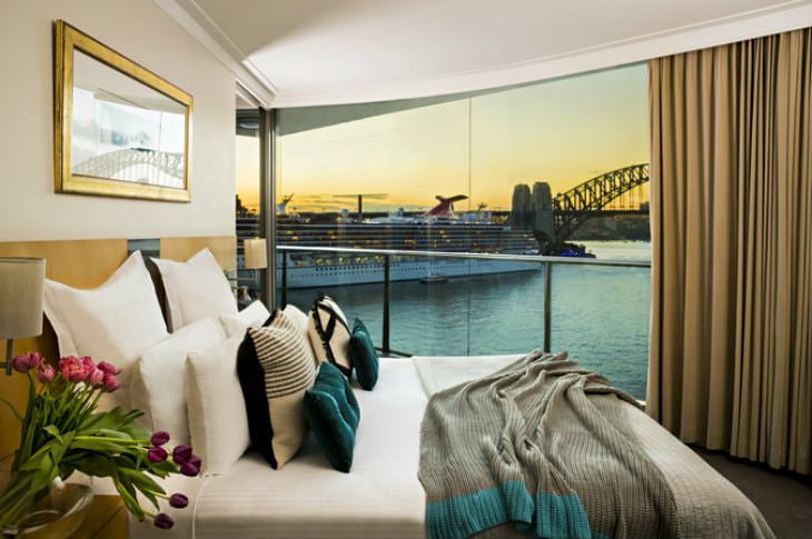 Simple and elegant beige guest room with glass wall overlooking Sydney Harbour Bridge