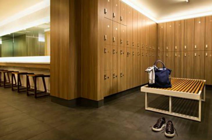 Upscale brown and beige locker room with one pair of tennis shoes and a blue gym bag