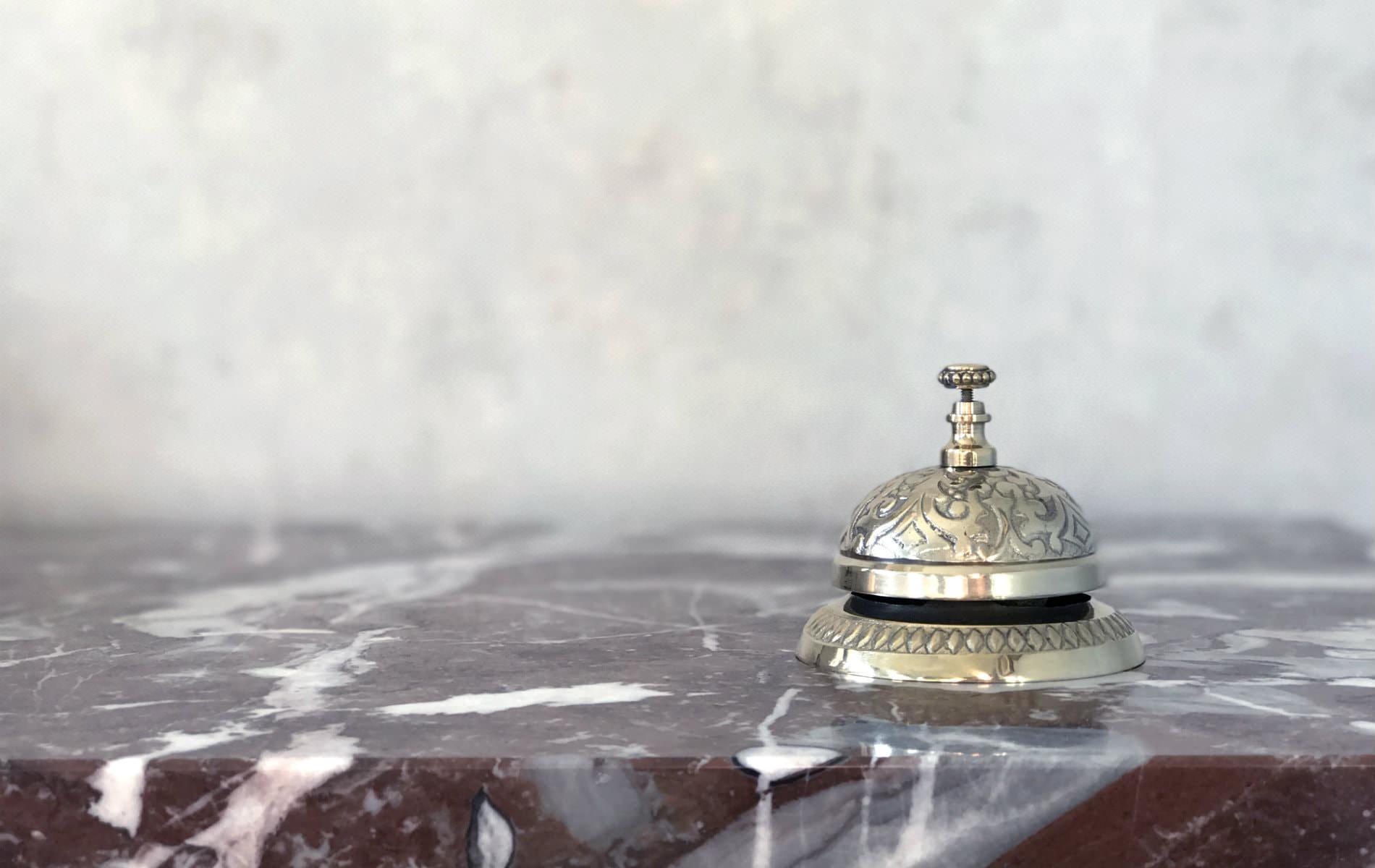 Close-up view of a gold ornate service bell on a stone countertop