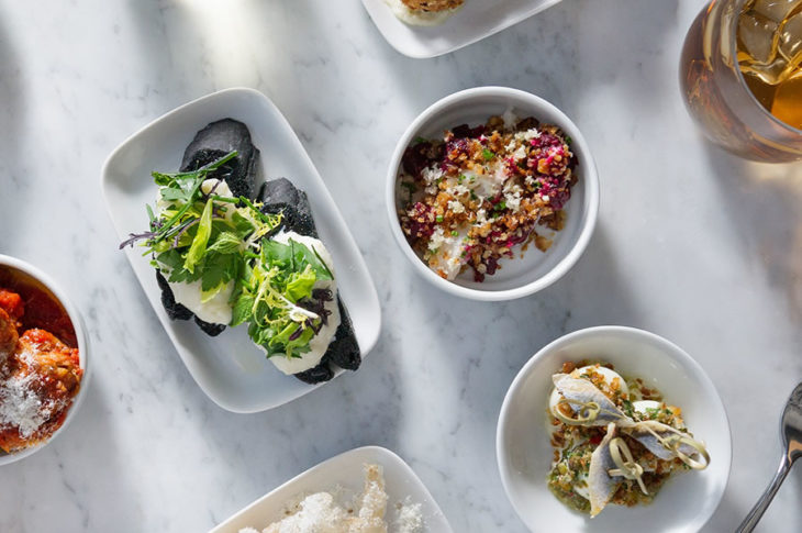 small dishes on white marble with green food white food and tomato