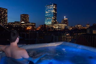 man in hot tub with blue lights and city skyline at night