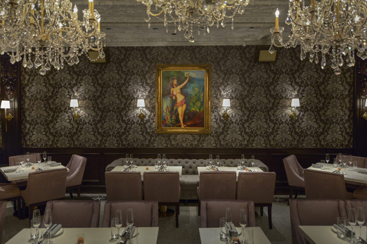 dining room with 5 crystal chandeliers and a painting of a woman with a blue background