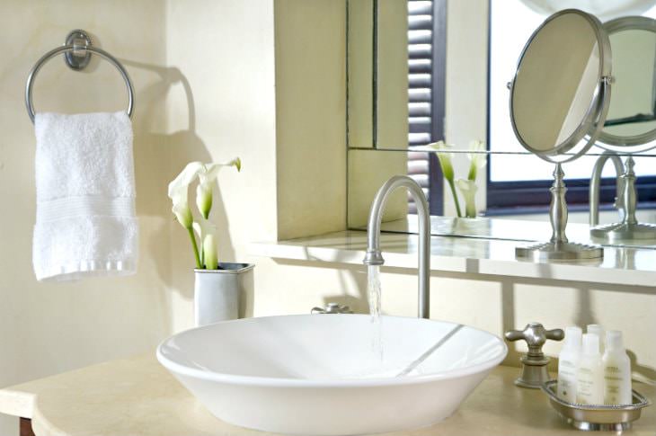 Close-up view of bathroom vanity with white vessel sink, sample size toiletries and silver fixtures