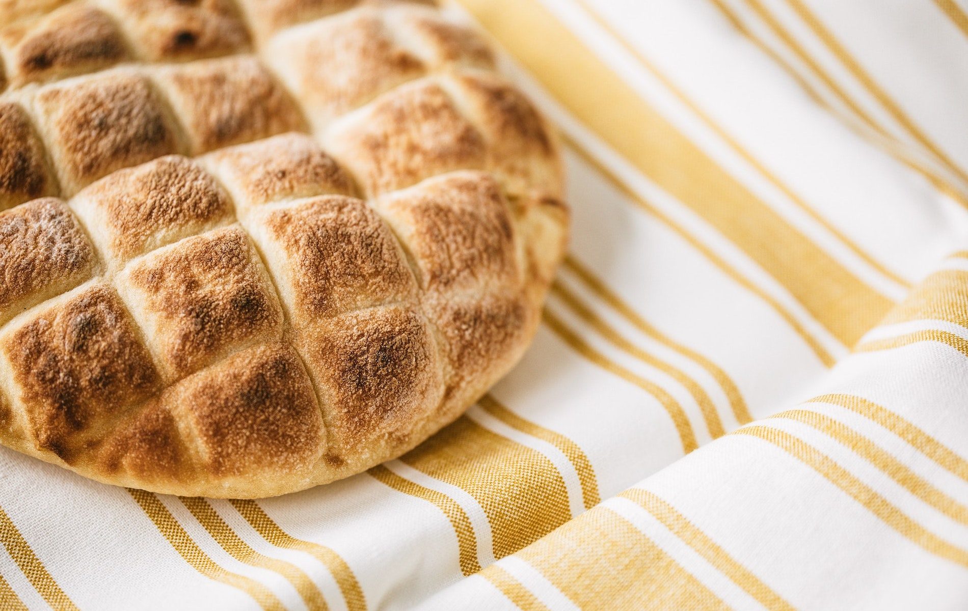 golden brown pita with checked designed on gold and white stripe towel
