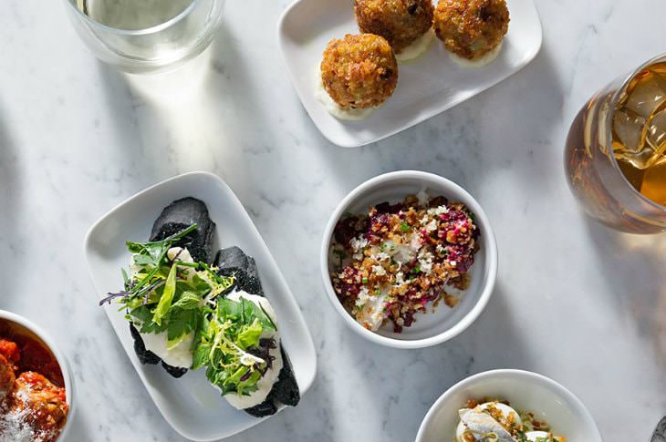 White bowls filled with colorful, artistic, gourmet dishes on a marble table