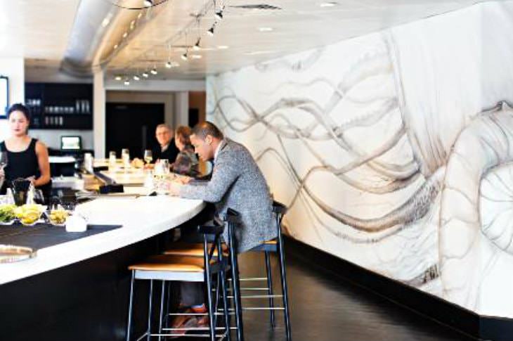 Elegant, modern black and white restaurant with three people sitting in stools at a curved bar