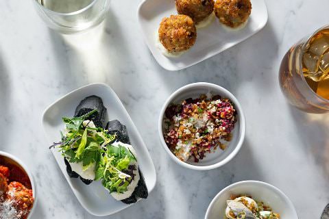 White bowls filled with colorful, artistic, gourmet dishes on a marble table