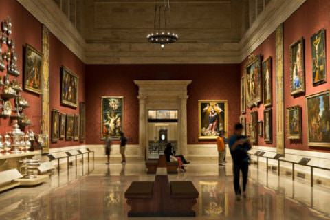 Elegant gallery with shiny marble floors and red walls filled with artwork