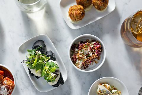 White bowls filled with colorful, artistic, gourmet dishes on a marble table