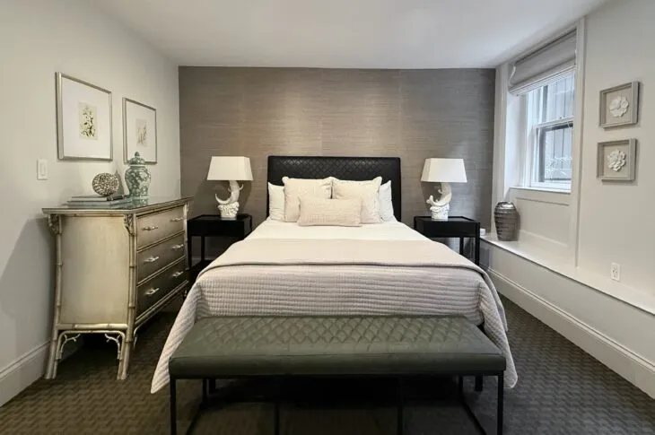Bedroom with centered bed, bench, and silver dresser.